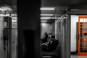 Men sitting in jail cell with orange door